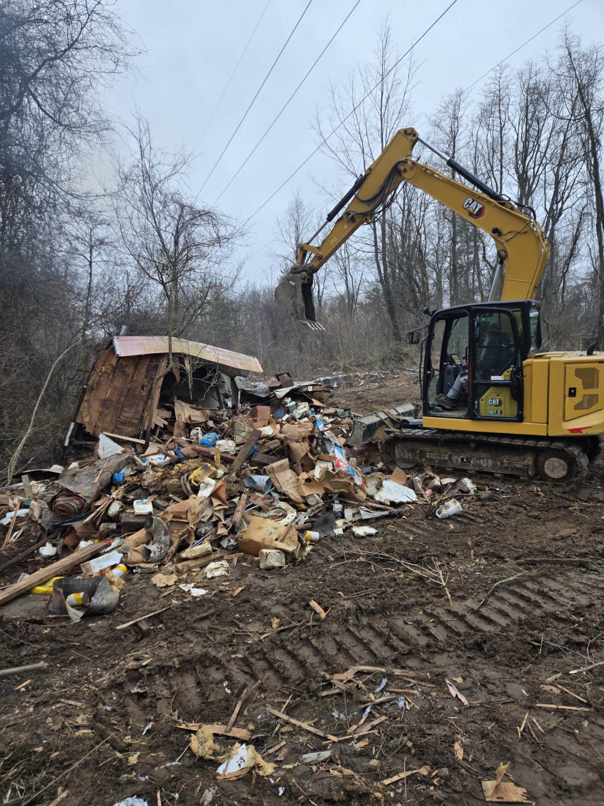 CAT excavator performing structure demolition and debris removal as part of excavation and site cleanup services.