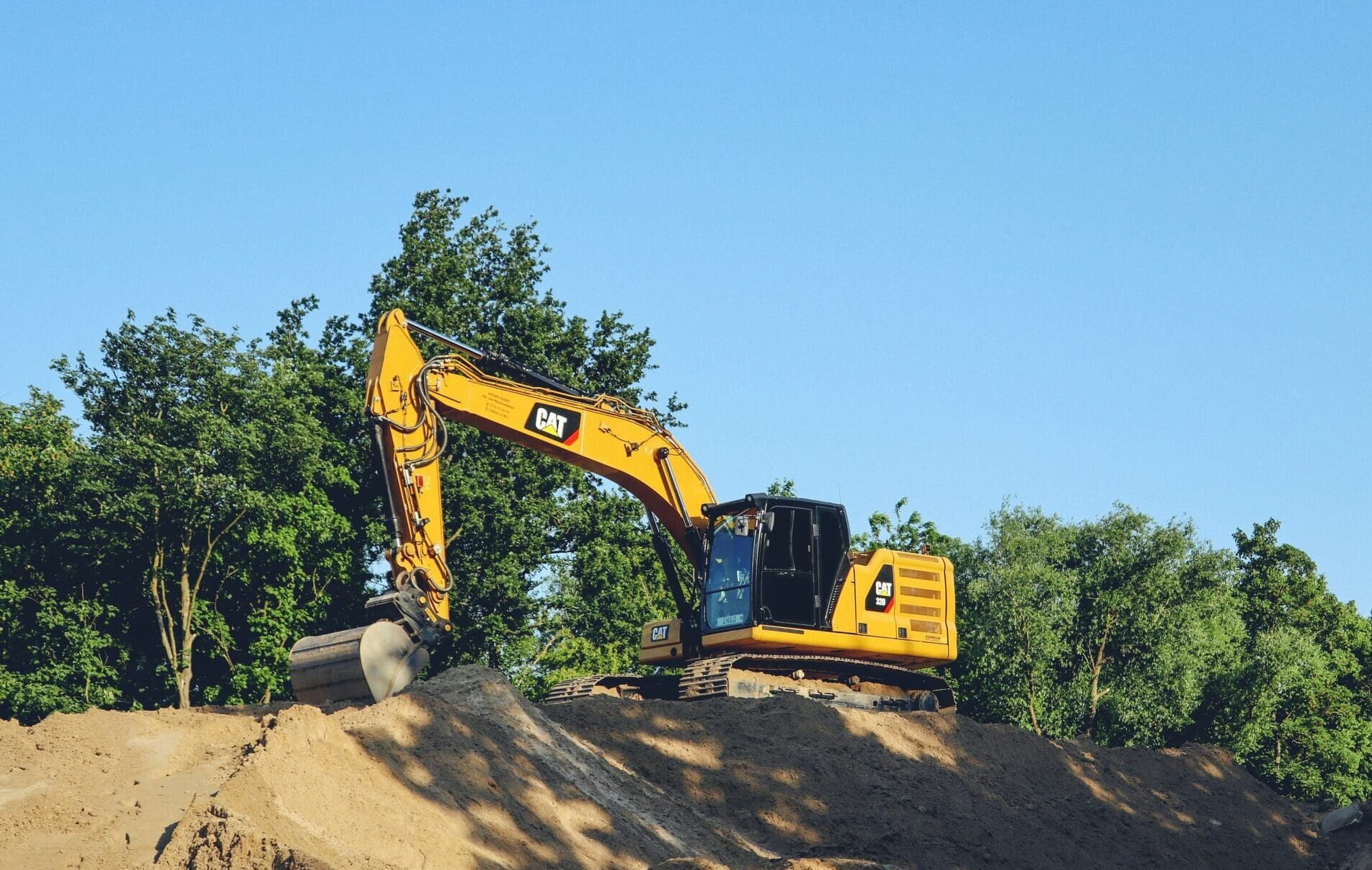 CAT excavator performing site grading and earthmoving for excavation and land preparation.